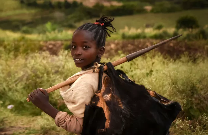 Young African girl carrying a load on her back in Ethiopia