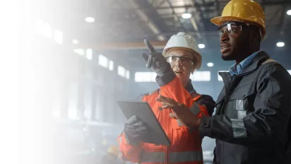 Two people in hard hats and safety glasses at work.