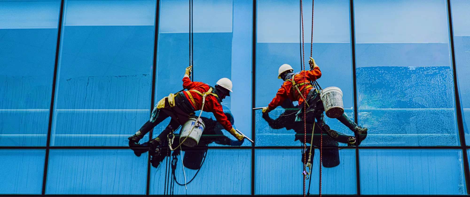 Two men painting on a building 