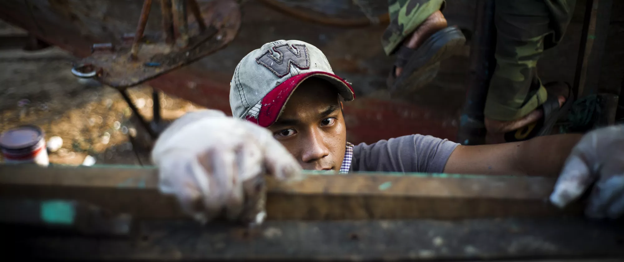 Young worker wearing gloves and a cap in a factory