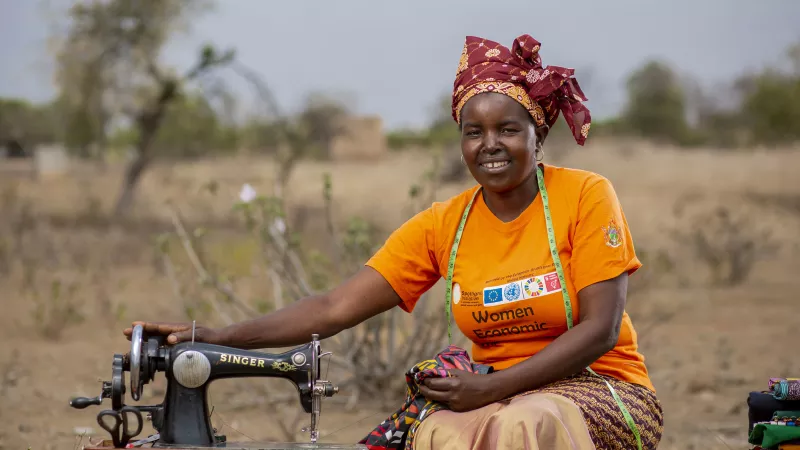 Martha Simango, fashion designer in Zimbabwe, sitting outside next to her sewing machine